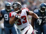 Atlanta Falcons Michael Turner (33) breaks away from Seattle Seahawks Brandon Mebane, left and David Hawthorne, right, to score a touchdown in the second quarter Sunday.