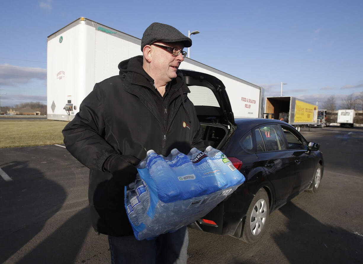 John Whitaker, executive director of Midwest Food Bank, carries a case of water that was donated Wednesday in Indianapolis. All of the water that was collected will be sent to Flint, Mich., where drinking water has been contaminated by lead.