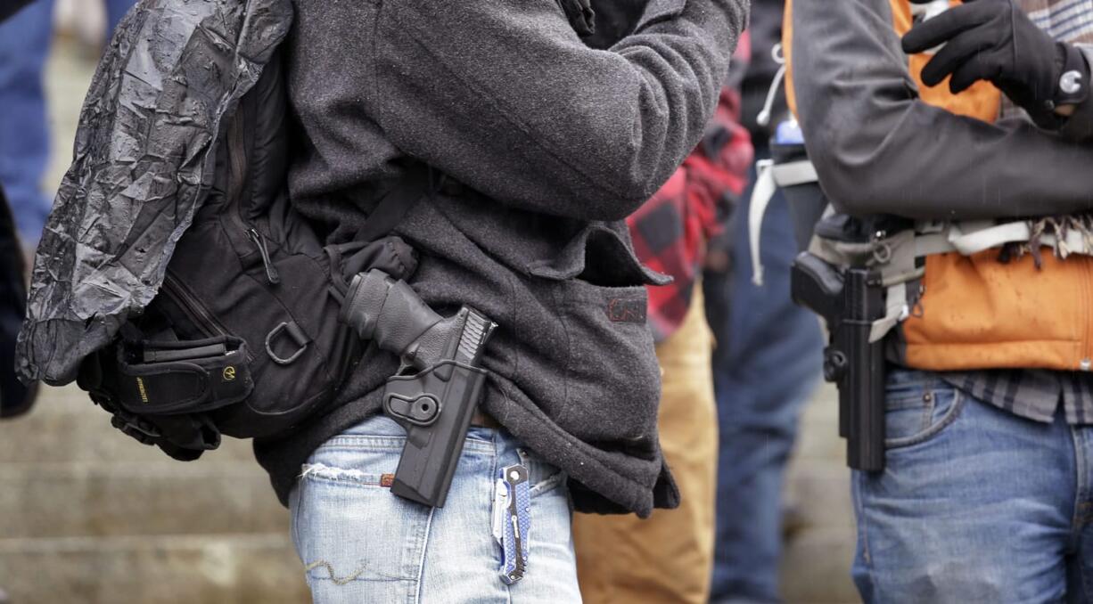 Men stand with pistols strapped at their sides at a gun rights rally on the steps of the Capitol on Friday in Olympia. Lawmakers and others spoke at the rally, which drew about 100 people, emphasizing legislative priorities and speaking against gun-related policies of President Barack Obama, like his recent executive actions to expand background checks to cover more firearms sold at gun shows, and elsewhere.