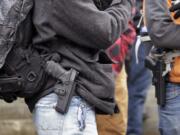 Men stand with pistols strapped at their sides at a gun rights rally on the steps of the Capitol on Friday in Olympia. Lawmakers and others spoke at the rally, which drew about 100 people, emphasizing legislative priorities and speaking against gun-related policies of President Barack Obama, like his recent executive actions to expand background checks to cover more firearms sold at gun shows, and elsewhere.