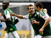 Portland Timbers' Mamadou Danso, from left, Eric Brunner and Kenny Cooper celebrate Cooper's goal against the Vancouver Whitecaps during the first half Sunday.