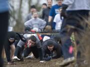 Participants go underneath an obstacle during the March Muddy Madness race that puts runners through a cross country course filled with mud, both natural and man-made obstacles and blackberry bushes on a farm in Felida.