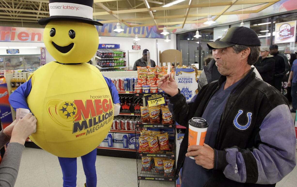 A customer smiles after receiving a free Mega Millions Lottery ticket from the Hoosier Lottery's Mega Millions mascot at a store in Zionsville, Ind., on Friday.