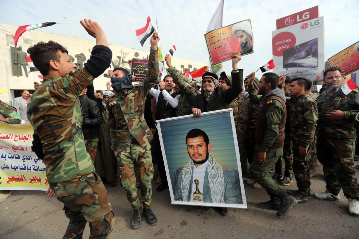 Shiite militiamen chant slogans against the Saudi government as one holds a poster of Abdul-Malik al-Houthi, a leader of Shiite rebels in Yemen, during a rally to protest the execution of Saudi Shiite cleric Sheik Nimr al-Nimr by Saudi Arabia last week in Tahrir Square, Baghdad, Iraq, on Wednesday.