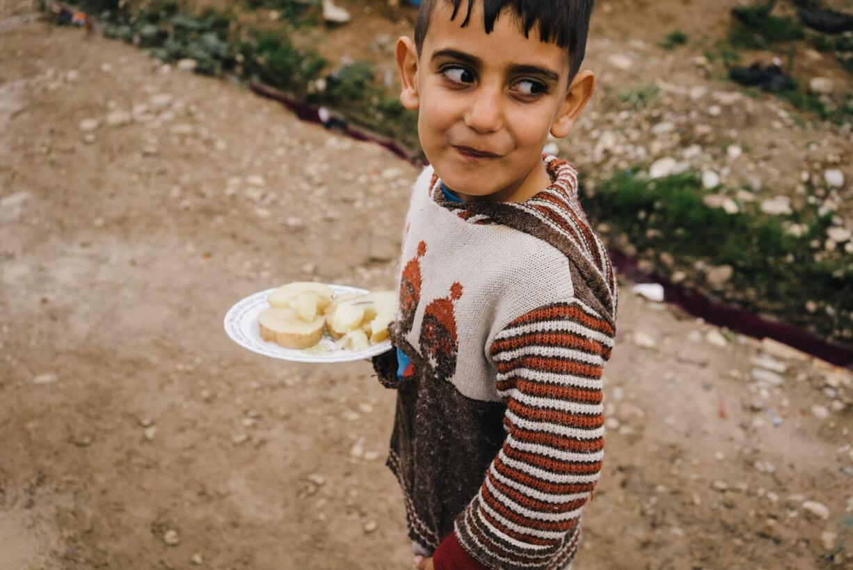 A Syrian boy walks Sunday in Kawergosk refugee camp in northern Iraq carrying a plate with boiled potatoes. According to the U.N. children&#039;s agency, malnutrition is a major threat among millions of refugees, as people eat less to conserve the little food they do have.