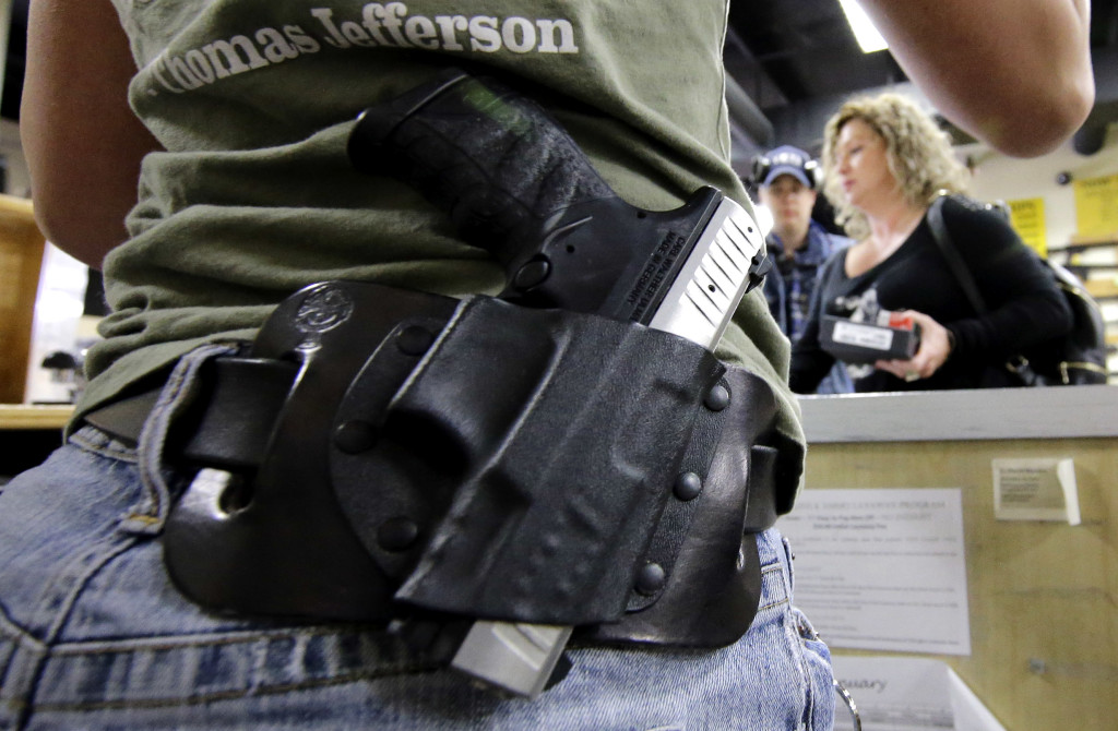 Kayla Brown, left, wears her gun on her hip while working at the Spring Guns and Ammo store Monday in Spring, Texas. President Barack Obama defended his plans to tighten the nation's gun-control restrictions on his own, insisting Monday that the steps he'll announce fall within his legal authority and uphold the constitutional right to own a gun. (AP Photo/David J.