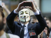 A protester with the &quot;Occupy Seattle&quot; movement wears a Guy Fawkes mask and takes a photo with a mobile phone as he demonstrates, in downtown Seattle. From New York to San Francisco to London, some of the demonstrators decrying a variety of society's ills are sporting stylized masks loosely modeled on a 17th-century English terrorist, whether they know it or not.