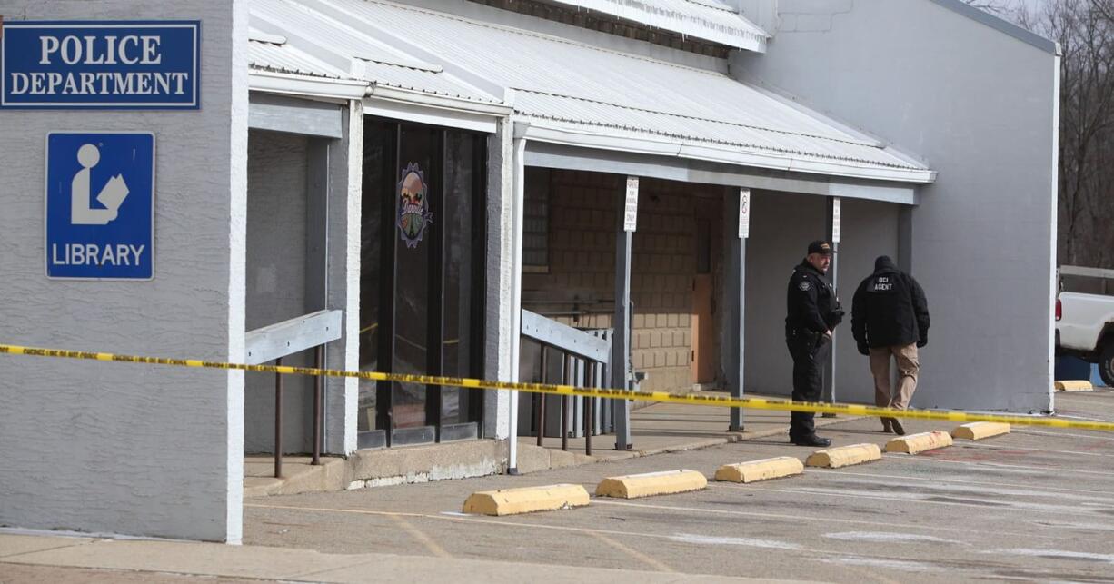 Danville Police Chief Daniel J. Weckessel, left, looks over the police station parking lot where Danville Officer Thomas Cottrell was gunned down, Monday in Danville, Ohio. A man whose ex-girlfriend reported that he was armed and looking to kill police was in custody on Monday suspected in the death of Cottrell.