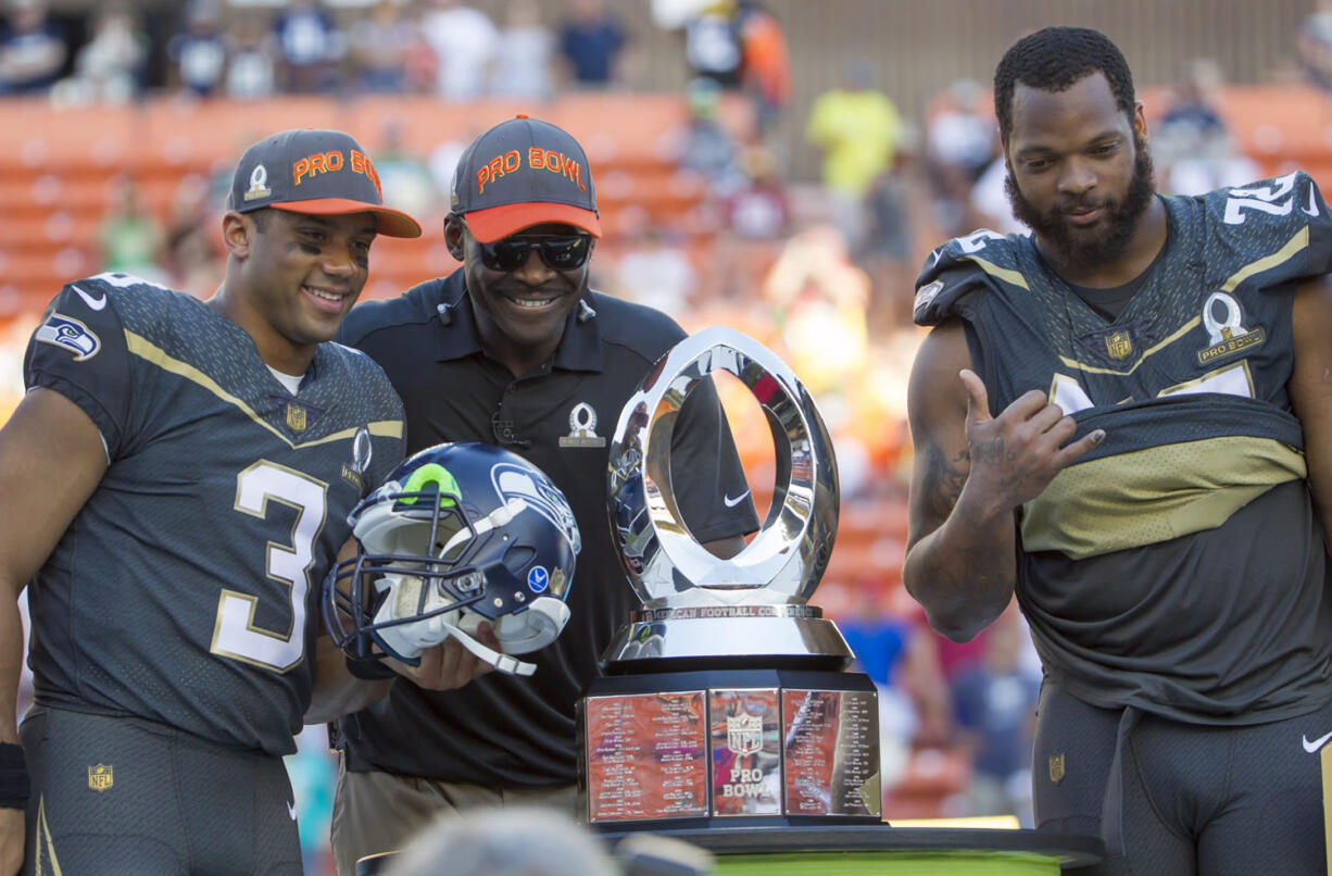 Michael Irvin, Pro Bowl legend team captain and Pro Football Hall of Famer, center, takes a photo with Seattle Seahawks quarterback Russell Wilson (3), who was named the offensive player of the game, and defensive end Michael Bennett, of Team Irvin, right, after the NFL Pro Bowl football game, Sunday, Jan. 31, 2016, in Honolulu. Team Irvin won 49-27.