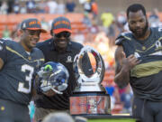 Michael Irvin, Pro Bowl legend team captain and Pro Football Hall of Famer, center, takes a photo with Seattle Seahawks quarterback Russell Wilson (3), who was named the offensive player of the game, and defensive end Michael Bennett, of Team Irvin, right, after the NFL Pro Bowl football game, Sunday, Jan. 31, 2016, in Honolulu. Team Irvin won 49-27.