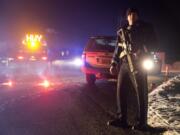 Sgt. Tom Hutchison stands in front of an Oregon State Police roadblock on Highway 395 between John Day and Burns by Oregon State police officers Tuesday, Jan. 26, 2016. Authorities say shots were fired Tuesday during the arrest of members of an armed group that has occupied a national wildlife refuge in Oregon for more than three weeks. The FBI said authorities arrested Ammon Bundy, 40, his brother Ryan Bundy, 43, Brian Cavalier, 44, Shawna Cox, 59, and Ryan Payne, 32, during a traffic stop on U.S. Highway 395 Tuesday afternoon. Authorities said another person, Joseph Donald O'Shaughnessy, 45, was arrested in Burns.