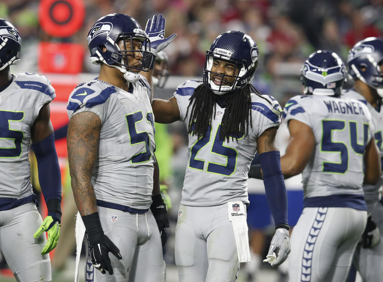 Seattle Seahawks cornerback Richard Sherman (25) celebrates a stop with outside linebacker Bruce Irvin (51) during the second half of an NFL football game against the Arizona Cardinals, Sunday, Jan. 3, 2016, in Glendale, Ariz.