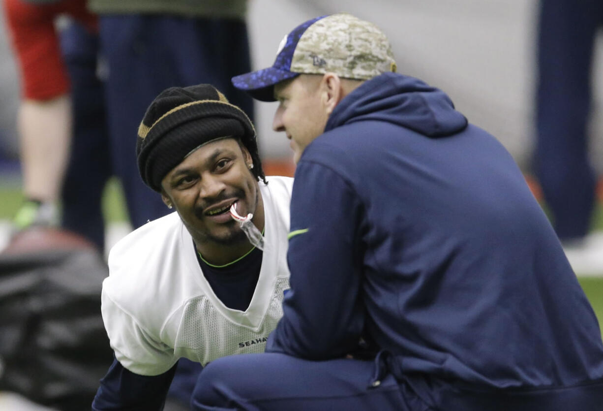 Seattle Seahawks running back Marshawn Lynch holds a candy cane in his mouth as he talks with offensive coordinator Darrell Bevell, right, before NFL football practice, Wednesday, Jan. 6, 2016, in Renton, Wash. Lynch has been recovering since having abdominal surgery last November. (AP Photo/Ted S.