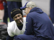 Seattle Seahawks running back Marshawn Lynch holds a candy cane in his mouth as he talks with offensive coordinator Darrell Bevell, right, before NFL football practice, Wednesday, Jan. 6, 2016, in Renton, Wash. Lynch has been recovering since having abdominal surgery last November. (AP Photo/Ted S.