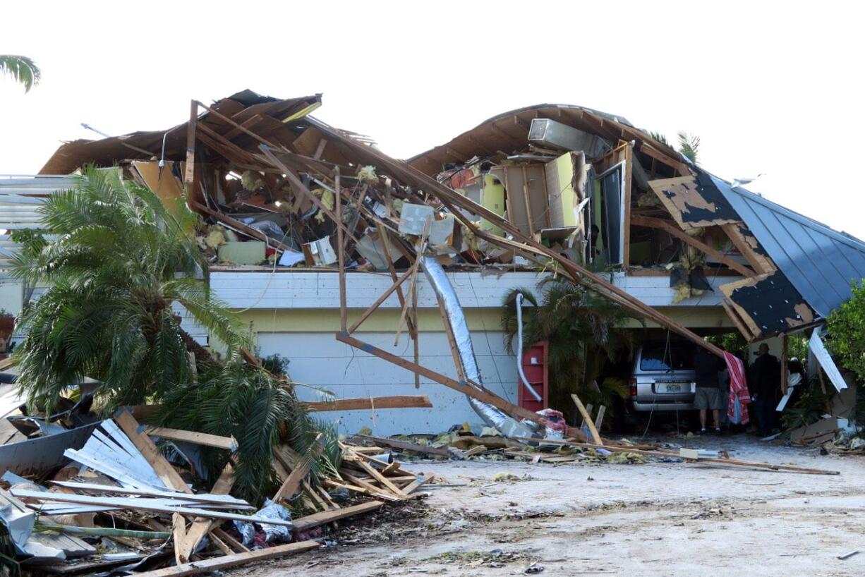 People look at debris and damage after a tornado struck in Siesta Key, Fla. Severe weather sparked a pair of tornadoes that ripped through central Florida before dawn Sunday.