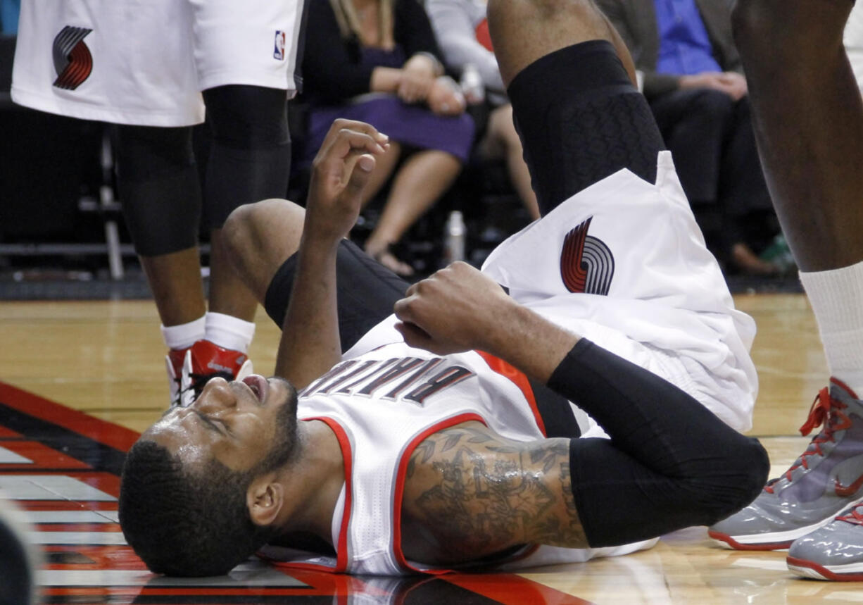 In this Monday, April 9, 2012, photo, Portland Trail Blazers forward LaMarcus Aldridge lies on the court in pain after a collision with another player during an NBA basketball game against the Houston Rockets in Portland, Ore.