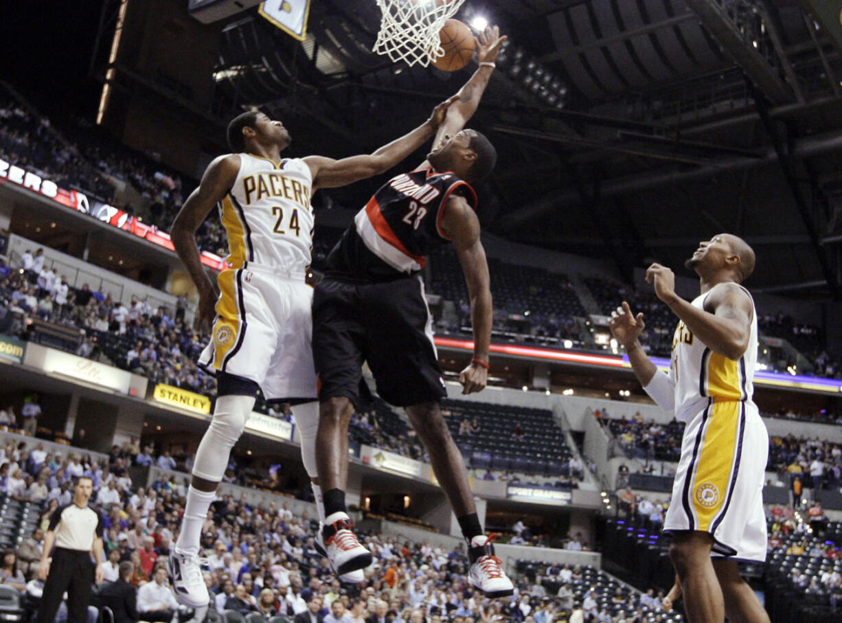 Portland Trail Blazers center Marcus Camby, center, is fouled by Indiana Pacers guard Paul George, left, as forward David West of the Pacers watches during the first half of an NBA basketball game in Indianapolis, Tuesday, March 13, 2012.