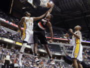 Portland Trail Blazers center Marcus Camby, center, is fouled by Indiana Pacers guard Paul George, left, as forward David West of the Pacers watches during the first half of an NBA basketball game in Indianapolis, Tuesday, March 13, 2012.