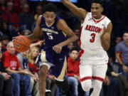 Washington guard Dejounte Murray (5) carries the ball past Arizona guard Justin Simon during the first half of an NCAA college basketball game, Thursday, Jan. 14, 2016, in Tucson, Ariz.