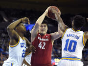 Washington State center Conor Clifford, center, tries to pass under pressure from UCLA forward Tony Parker, left, and guard Isaac Hamilton during the first half of an NCAA college basketball game Saturday, Jan. 30, 2016, in Los Angeles. (AP Photo/Mark J.