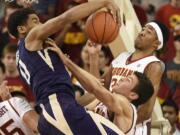 Washington forward Marquese Chriss, left, reaches for a rebound in front of Southern California guard Elijah Stewart, right, and Nikola Jovanovic, bottom during the second half of an NCAA college basketball game in Los Angeles, Saturday, Jan. 30, 2016. Southern California won 98-88.