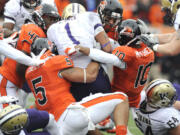 Oregon State's players, including Cameron Collins (5), Lance Mitchell (10) and Michael Doctor (40), tackle Washington's Chris Polk (1) during the first half Saturday.