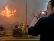 Douglas Pratt records video on his phone of a two-alarm fire at his neighbor's Hazel Dell home on Monday.