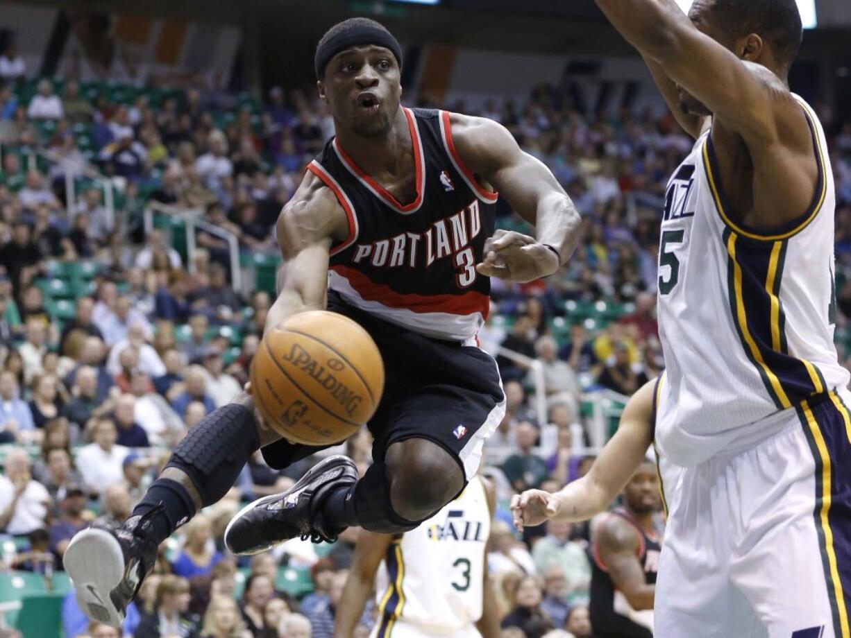 Portland's Jonny Flynn (3) makes a pass around Utah's Derrick Favors during the first half Thursday at Salt Lake City.