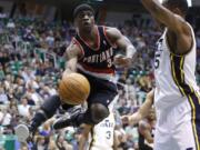 Portland's Jonny Flynn (3) makes a pass around Utah's Derrick Favors during the first half Thursday at Salt Lake City.