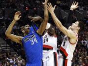 Dallas forward Brandan Wright, left, battles for a rebound with the Portland's Luke Babbitt, right, and Hasheem Thabeet during the first half Friday.