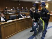 Washington State Patrol troopers remove one of several protesters who disrupted a meeting of the Senate Ways and Means Committee by standing and shouting their opposition to budget cuts at the Capitol in Olympia on Tuesday.