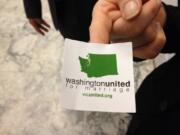 A supporter of gay marriage hands out stickers outside an overflow room for a Senate committee hearing on proposed legislation that would legalize same-sex marriage on Monday at the Capitol in Olympia, Wash.