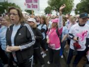 Breast cancer survivor Nell Perdue, center, then 39, of Vancouver reaches skyward as she cheers at the start of the 5K walk during the Race for the Cure in downtown Portland in 2011.