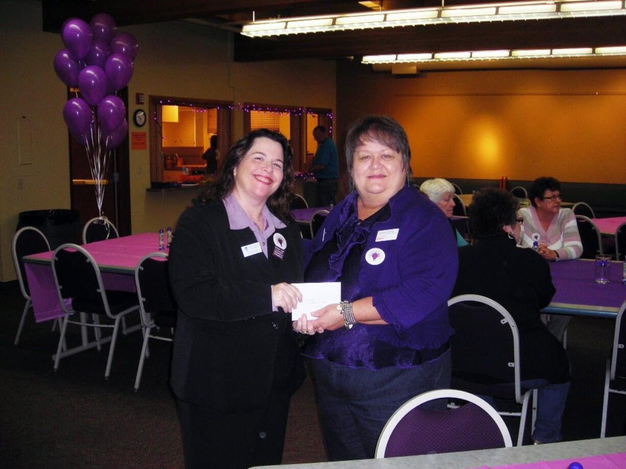 Debra Adams, right, director of YWCA Clark County's SafeChoice Domestic Violence program, shown here accepting a contribution from Michelle Bart of Soroptimist International of Southwest Washington, is resigning as part of her own plan to save SafeChoice.