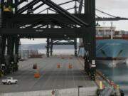 A cargo ship sits docked at the Port of Tacoma as a lone truck crosses normally bustling cargo-handling lanes in May 2008.