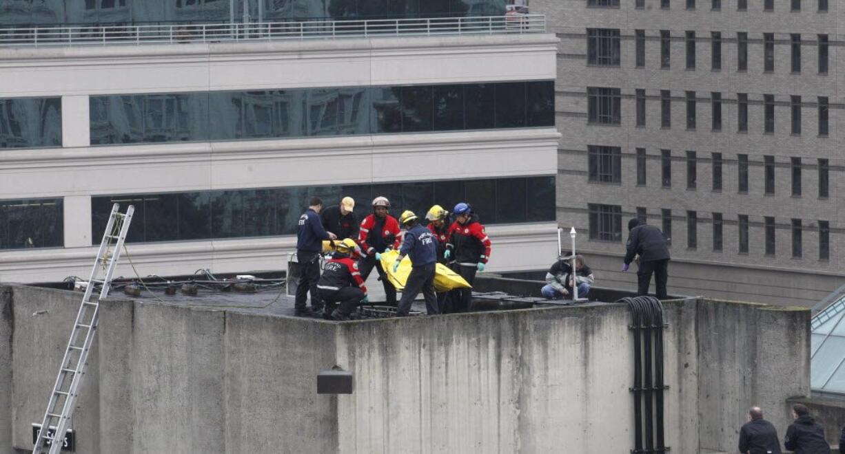 Portland Firemen move the body of a man shot by police Wednesday in Portland.