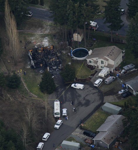 The remains of a house smolder, left, where a fire killed Josh Powell and his two sons Sunday in Graham.