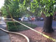 A small crowd waits while firefighters work at the Prune Tree Apartments, where one unit was damaged by a fire Tuesday afternoon.