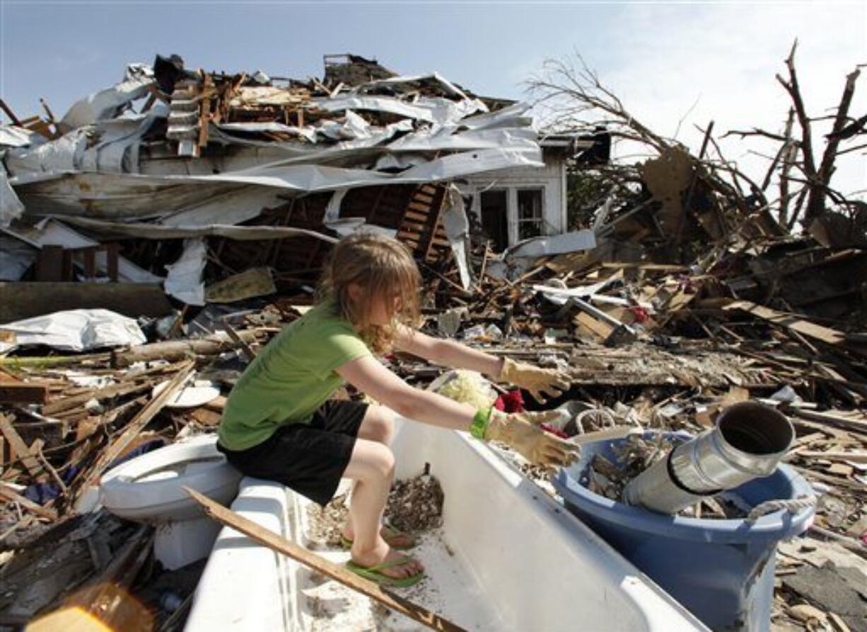 Laura Cobb, 11, cleans debris from a bathtub while helping with clean-up at her destroyed home in Joplin, Mo. Monday, May 30, 2011. Four members of her family escaped injury by seeking refuge in the tub when an EF-5 tornado tore through much of the city May 22, damaging a hospital and hundreds of homes and businesses and killing at least 139 people.