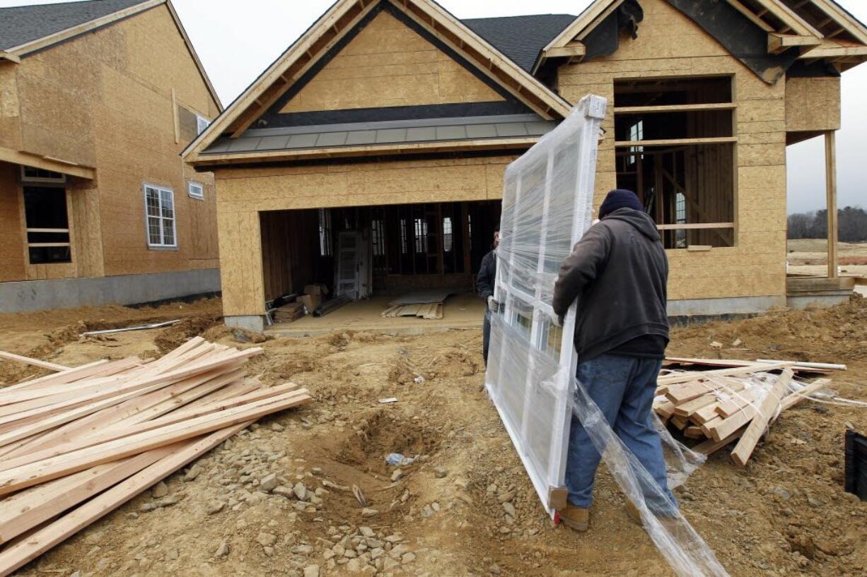 In this Feb. 8, 2012 photo, two workers carry a window for a home under construction in a new subdivision by Toll Brothers, in Yardley, Pa. Thirty-six new-home permits valued at $11.1 million were issued to build homes in unincorporated parts of Clark County last month, according to the Clark County Community Development Department.