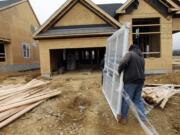 In this Feb. 8, 2012 photo, two workers carry a window for a home under construction in a new subdivision by Toll Brothers, in Yardley, Pa. Thirty-six new-home permits valued at $11.1 million were issued to build homes in unincorporated parts of Clark County last month, according to the Clark County Community Development Department.