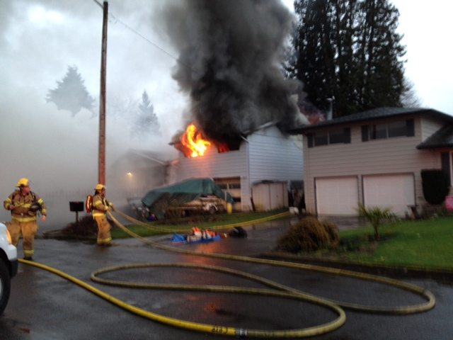 Flames lick from the second floor of a Hazel Dell home Monday afternoon.