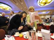 Kathy Corwin, right, shares artwork from children about who their heroes are, with Melody Bazzel, who was recognized for her efforts as an animal rescue hero at the 15th annual American Red Cross Real Heroes Breakfast on Friday in Vancouver.