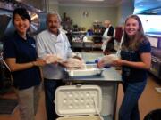 People at St. Vincent&#039;s Food Pantry in Reno, Nev., display fish fillets they received with an assist from a Vancouver company, Smith-Root.