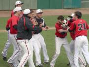 Camas baseball players and coaches celebrate with Justin Webb (center) after he beat out the base hit that won the district title Thursday, at Propstra Park in Vancouver.