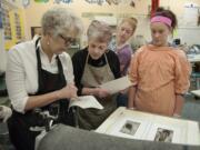 Art teacher Fae Moeller, from left, checks a print with Sharri LaPierre of North Bank Artists, eighth-grader Arianna Bollens, 13, and seventh-grader Darrian Gunderson, 12, on Thursday at Thomas Jefferson Middle School.