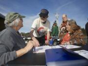 Volunteer Kathryn Thornton, far left, checks in Leonard Barnes, Dale Barnes and Linda Barnes (left to right), of La Center, at the Lewis River Mobile Food Bank distribution site in the unincorporated View area near La Center.