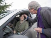 The Reverend Tom Warne offers  "Ashes to Go "  to passersby Julie Davis on Ash Wednesday in front of Church of the Good Shepherd in Vancouver Wednesday February 10, 2016.