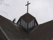 Joel Perez handles a pressure-wash sprayer about 120 feet above the ground Friday morning at St. Joseph Catholic Church.