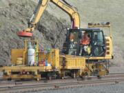 A worker uses an electromagnet to remove metal debris during BNSF rail upgrades in Wishram on Tuesday. The company is investing $220 million in infrastructure upgrades in Washington state.